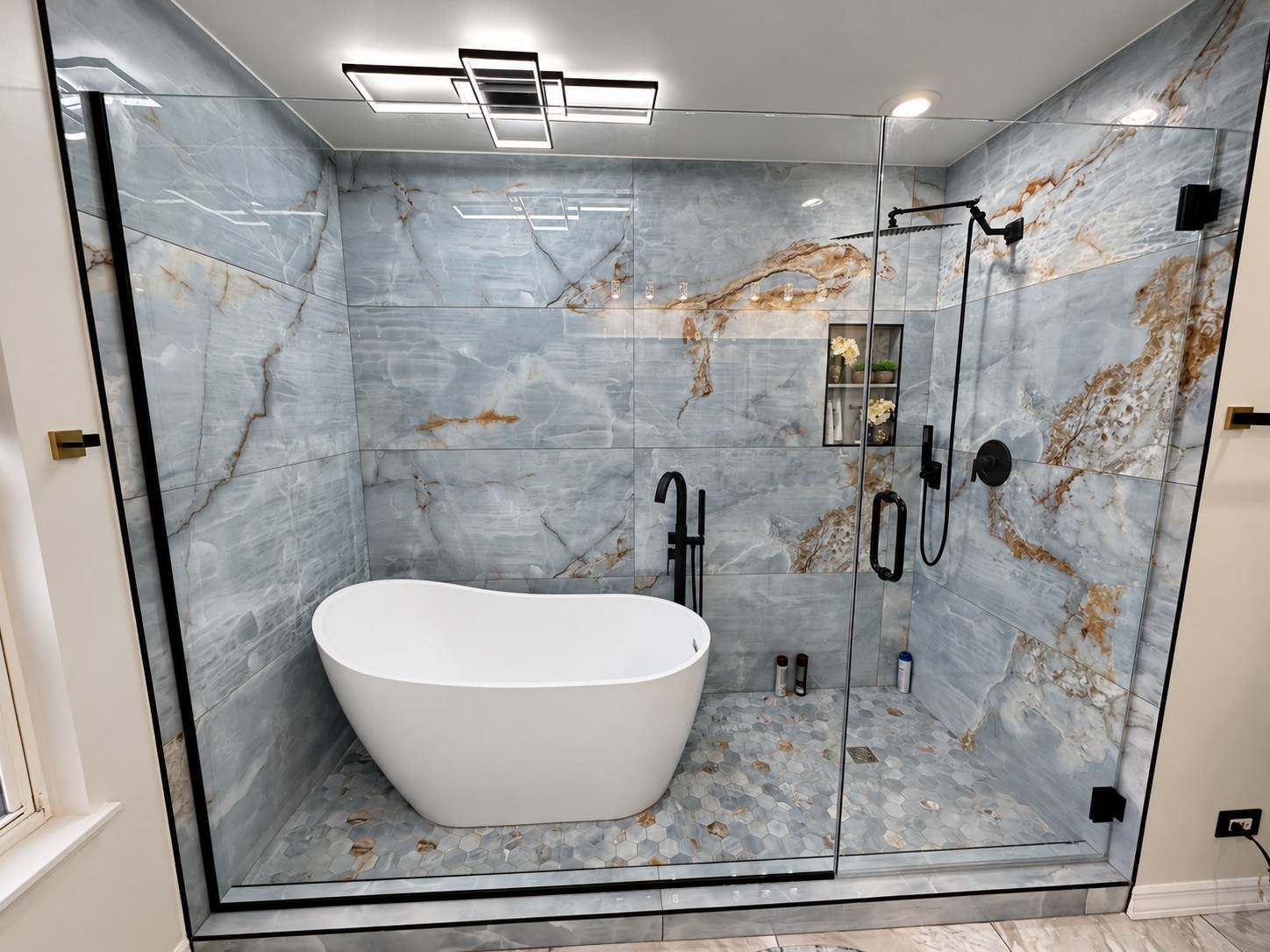 Blue stone-look tile bathroom with freestanding tub, glass shower enclosure and hexagonal mosaic floor.